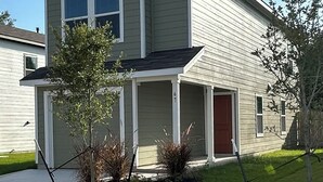 En toetagehus med veranda, garage og en lille forhave med beplantning.