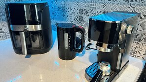 En kaffemaskine med digitalt display og kaffekande på en bordplade.