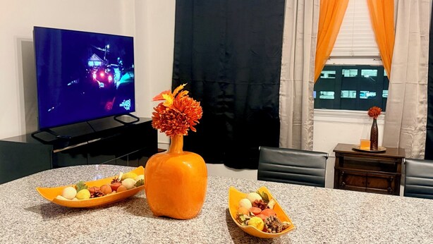 Ein Wohnzimmer mit Fernseher, einer Blumenvase und zwei Obstschalen auf einer Granitabdeckung.
