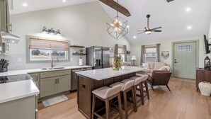 A spacious kitchen with a central island, bar stools, a refrigerator, and a ceiling fan. - Charming 2 Bedroom 2 Bath Cottage near the lake. (Campbellsville)