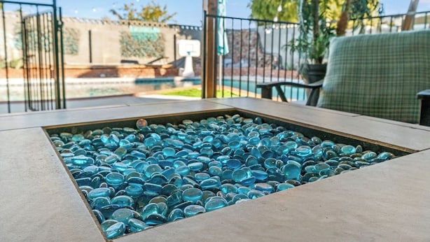 Eine Terrasse mit einem Glastisch, umgeben von einem Metallzaun.
