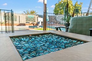 A patio with a glass-tiled table surrounded by a metal fence.