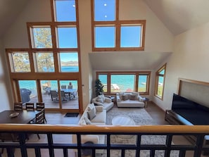 Amplia sala de estar con un gran ventanal con vistas panorámicas, un rincón de estar acogedor y un comedor con mobiliario de exterior.