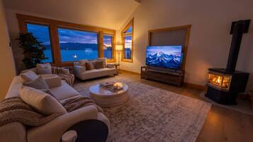 A living room with a sofa, a coffee table, a TV, a fireplace, and large windows with a view.