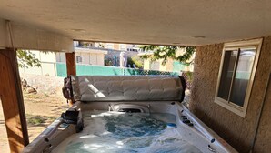 Een bubbelbad met een stenen buitenkant, een raam aan de zijkant en uitzicht op de achtertuin.