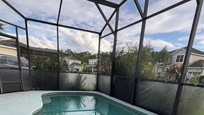 En swimmingpool med en glasvägg runt om, omgiven av ett staket av metall, och hus i bakgrunden.