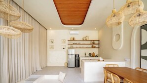 Eine moderne Küche mit Kochinsel, integrierten Geräten und einem Essbereich mit Holztisch und Stühlen.