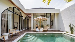 Ein moderner Poolbereich mit einer verglasten Terrasse, Holzdeck und Liegestühlen.