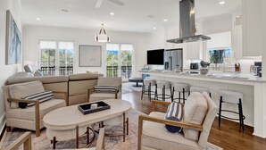 A modern kitchen with white cabinetry, a central island, and a ceiling fan. - Live in Luxury at This Brand New Tybee Island Escape | Heated Pool Access (Tybee Island)