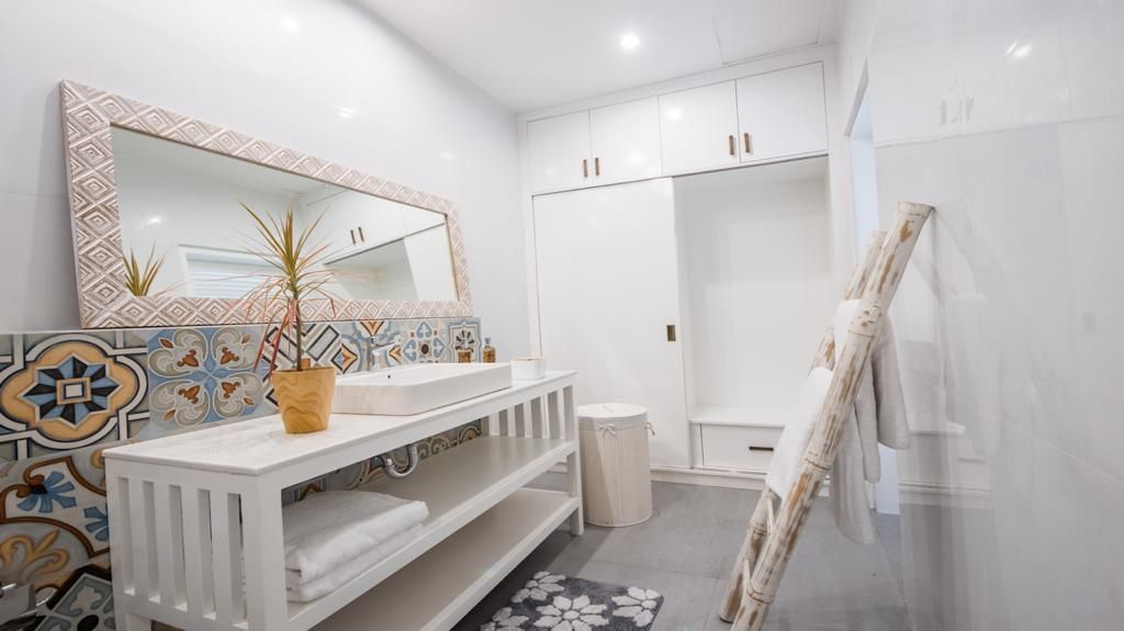 A modern bathroom with a white vanity, a large mirror, and a shower area.