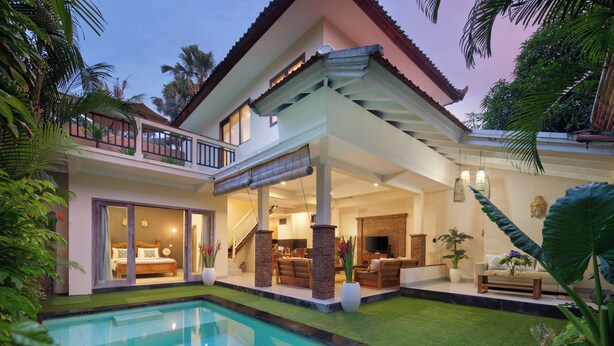 A two-story house with a swimming pool, a balcony, and a well-lit interior. - Red Lotus Villa Seminyak (Seminyak)