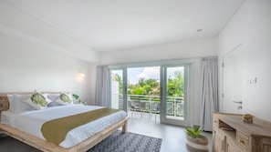 A hotel room with a bed, a balcony, and a view of greenery. - Red Lotus Villa Seminyak (Seminyak)