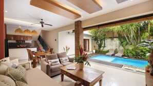A spacious living area with a pool, a dining area, and a kitchen. - Red Lotus Villa Seminyak (Seminyak)