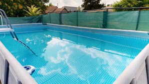 An indoor swimming pool with clear blue water, a ladder, and a safety ring. - Holiday apartment with sauna, pool, hot tub and bathing barrel (Balatonszabadi)