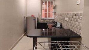A narrow kitchen with a black countertop, a water heater, and a tiled backsplash. - Peaceful 2-bedroom apartment in charming Colva perfect for relaxing (Fatona)