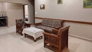 A living room with a sofa, two armchairs, a coffee table, and a ceiling fan. There are two framed pictures on the wall. - Peaceful 2-bedroom apartment in charming Colva perfect for relaxing (Fatona)