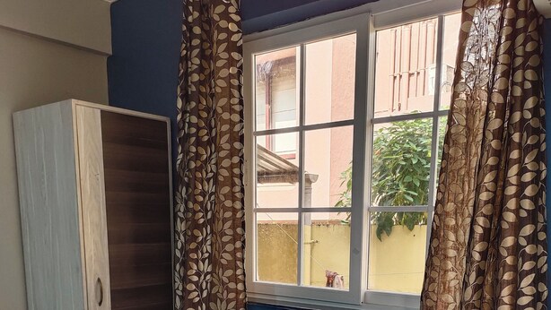 Une chambre à coucher avec un lit, une armoire et une fenêtre avec des rideaux.