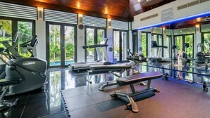 A modern gym with various exercise equipment, large windows, and a polished floor.