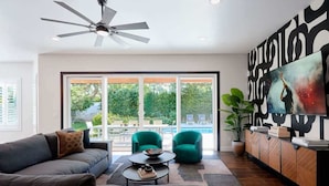 A modern living room with a sofa, two armchairs, a coffee table, a ceiling fan, and a large abstract painting. - Contour - Priv Pool- Fun Design- Mins 2 everything (Phoenix)