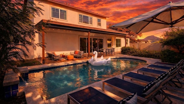 A swimming pool with lounge chairs and a swan float, surrounded by a house with a patio and outdoor furniture. - Contour - Priv Pool- Fun Design- Mins 2 everything (Phoenix)