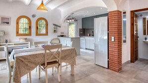 Un comedor amplio con una mesa dispuesta para cuatro, una cocina con electrodomésticos modernos y una chimenea de ladrillo.