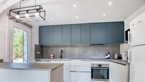 Una cocina moderna con una isla central, electrodomésticos integrados y un amplio ventanal.