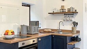 A modern kitchen with a wooden countertop, built-in appliances, and a heart-shaped decoration on the wall. - Daveys Barn, Brendon Hill on Exmoor (Nr Watchet)