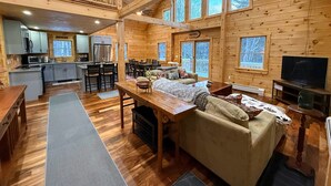 Une cabine spacieuse comprenant un coin repas, une cuisine et un salon confortable avec un canapé et une télévision.