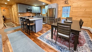 Une cuisine chaleureuse, aménagée dans le style d’un chalet, avec des murs en bois, un îlot central et un coin repas.