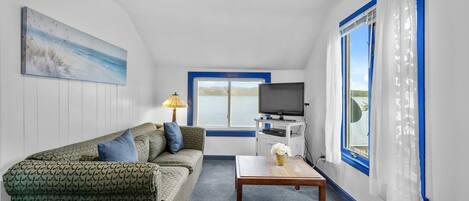 A room with a sofa, a table, a TV, and a window with curtains.