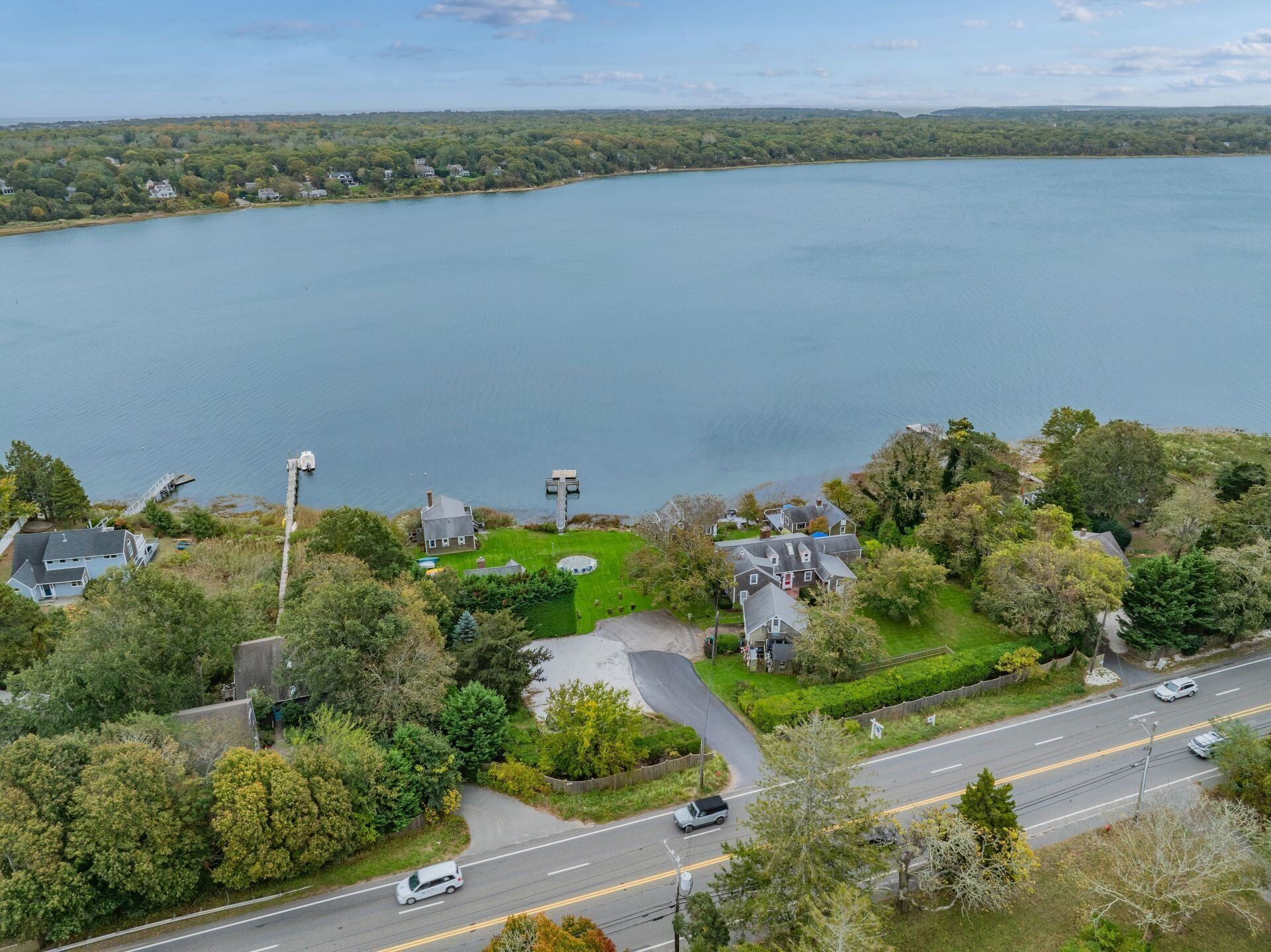 Une propriété au bord du lac, dotée d’un chemin d’accès, d’un quai et de maisons entourées d’arbres.