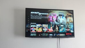A television mounted on a wall displaying a movie selection interface. - Cozy 1-bedroom studio in adorable Orlando with AC (Orlando)