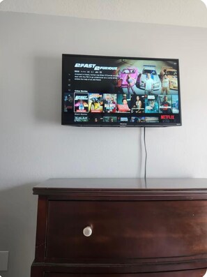 A television mounted on a wall displaying a movie selection interface. - Cozy 1-bedroom studio in adorable Orlando with AC (Orlando)