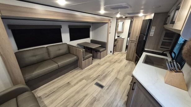 A compact RV interior with a sofa, a small table, and a kitchenette. - Cozy 1-bedroom studio in adorable Orlando with AC (Orlando)