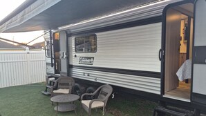 A Coleman RV with a covered patio area, including outdoor furniture and a step leading to the entrance. - Cozy 1-bedroom studio in adorable Orlando with AC (Orlando)