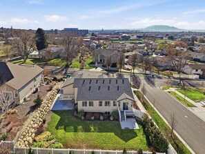 A suburban house with a large front yard, a driveway, and a street view in the background.