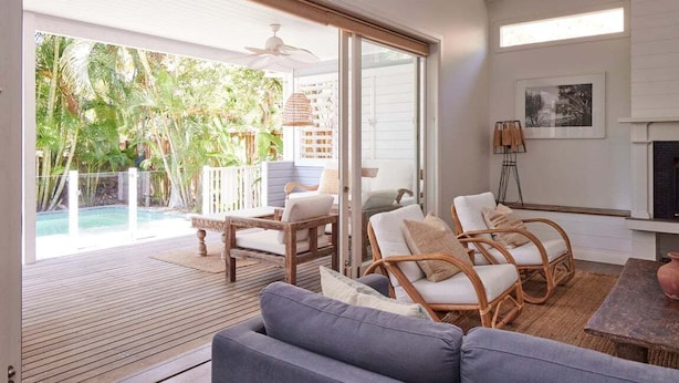 Amplia sala de estar con una terraza de madera, piscina y chimenea.