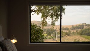 Un dormitorio con un ventanal grande que da a un paisaje rural.