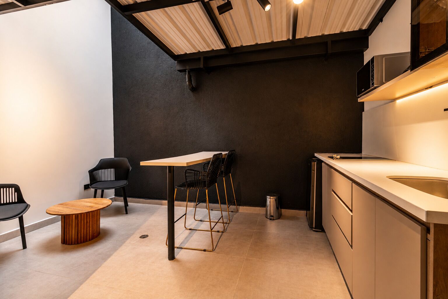 Una cocina moderna con una mesa y sillas de madera, una silla negra y un lavamanos de acero inoxidable.