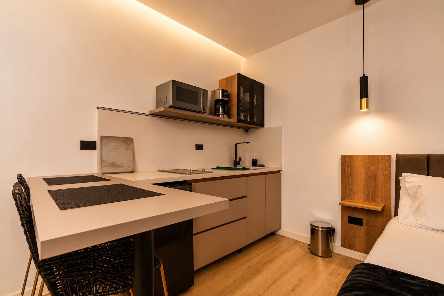 Een kleine hotelkamer met kitchenette, eethoek en een bed.
