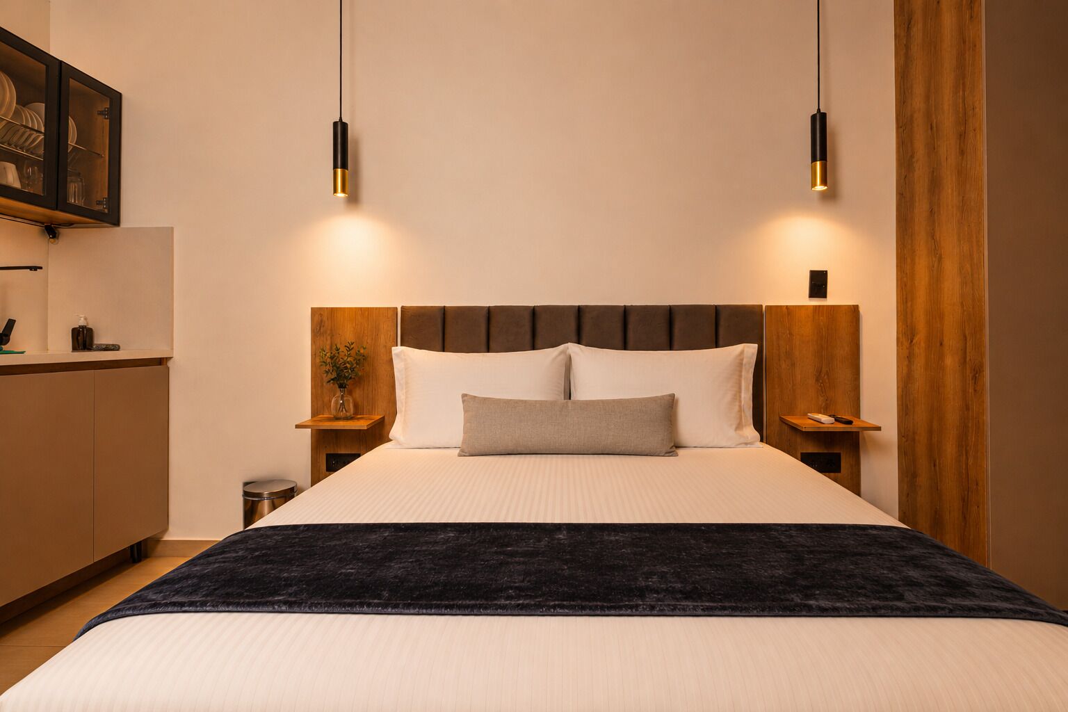 Une chambre moderne avec un grand lit, une tête de lit en bois, des tables de chevet et des lampes suspendues.