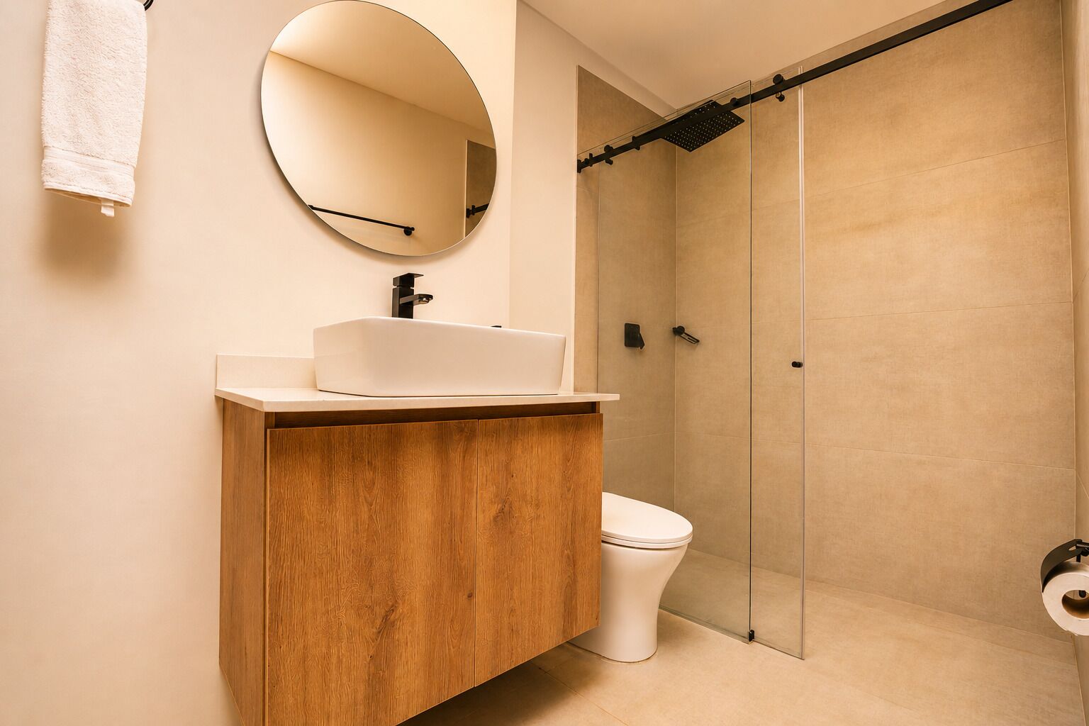 A modern bathroom with a wooden vanity, a round mirror, a toilet, and a glass shower enclosure.