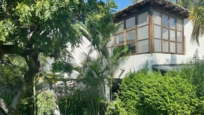 Una casa con pared de piedra, una ventana y abundante vegetación.
