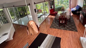 Amplia sala de estar con un gran ventanal corredera que da a un balcón, comedor con mesa y sillas, y zona de estar con sofá y televisor.