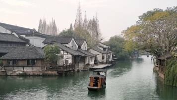 A traditional wooden boat on a calm river, surrounded by old-style buildings with tiled roofs.