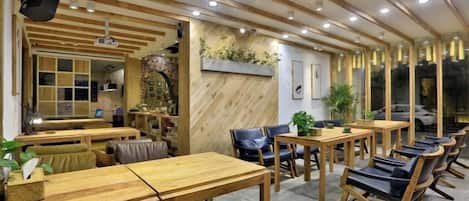 Um restaurante com mesas e cadeiras de madeira, área de bar e um espaço de estar com bancos acolchoados.