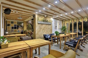 Un restaurante con mesas y sillas de madera, una zona de bar y un área de asientos con bancos acolchados.