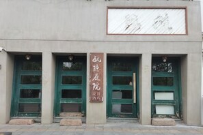 A building facade with three green-framed windows and a vertical sign with text. - Wuzhen Yuyin Courtyard Design Hotel (South Gate of Xizha Scenic Area) (Tongxiang)