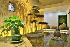 A tranquil indoor garden with a water feature, bonsai trees, and a seating area. - Wuzhen Yuyin Courtyard Design Hotel (South Gate of Xizha Scenic Area) (Tongxiang)