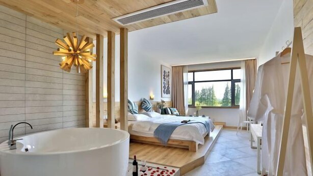Ein modernes Schlafzimmer mit einer großen Badewanne, einem Bett mit Blick ins Freie und einer Holzbalkendecke.